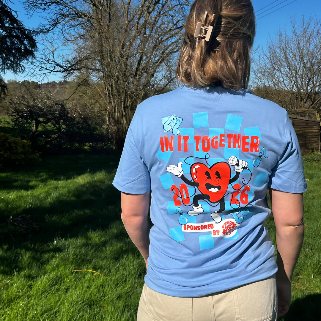 Person wearing a blue t-shirt with a graphic design and text outdoors.