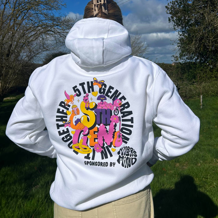 Person wearing a white hoodie with colorful text and graphics outdoors.