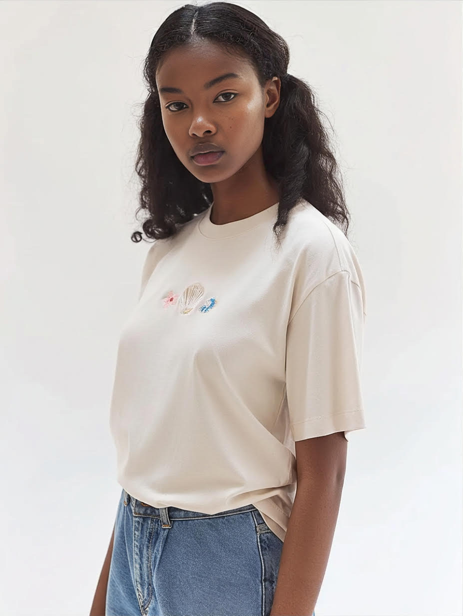 Person wearing a beige t-shirt with a colorful design on a plain background