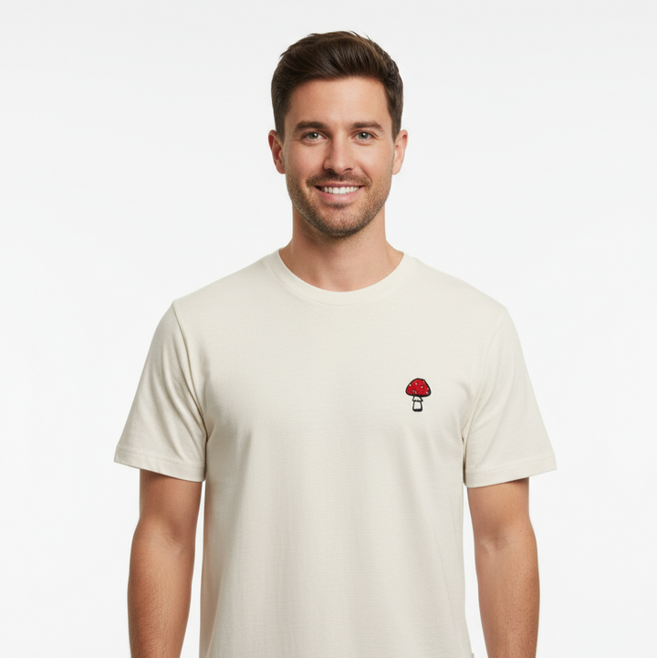 Man wearing a beige t-shirt with a small graphic on a white background