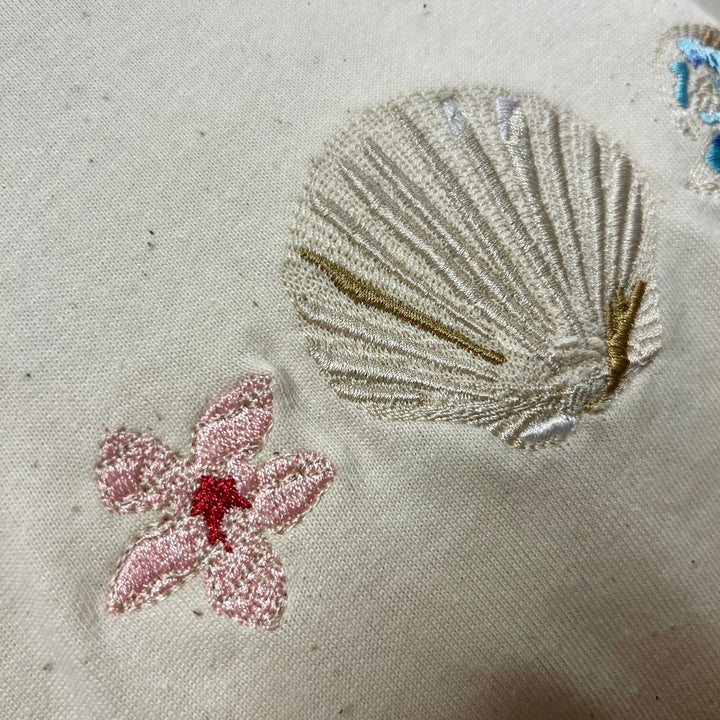 Embroidered shell and flower design on organic cotton 