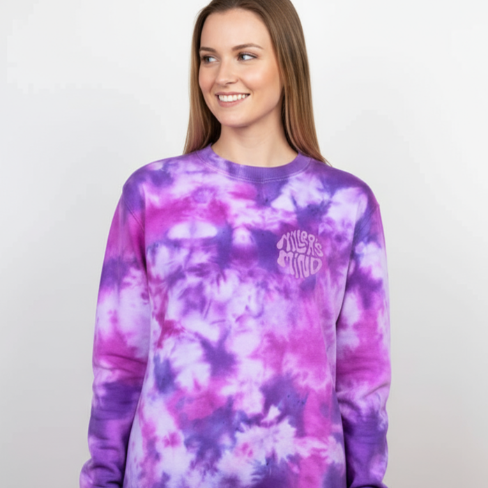 Person wearing a purple and pink tie-dye sweatshirt with a logo on a plain background